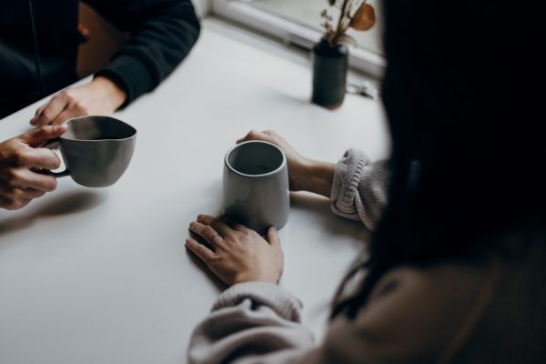 two people having coffee on a white desk